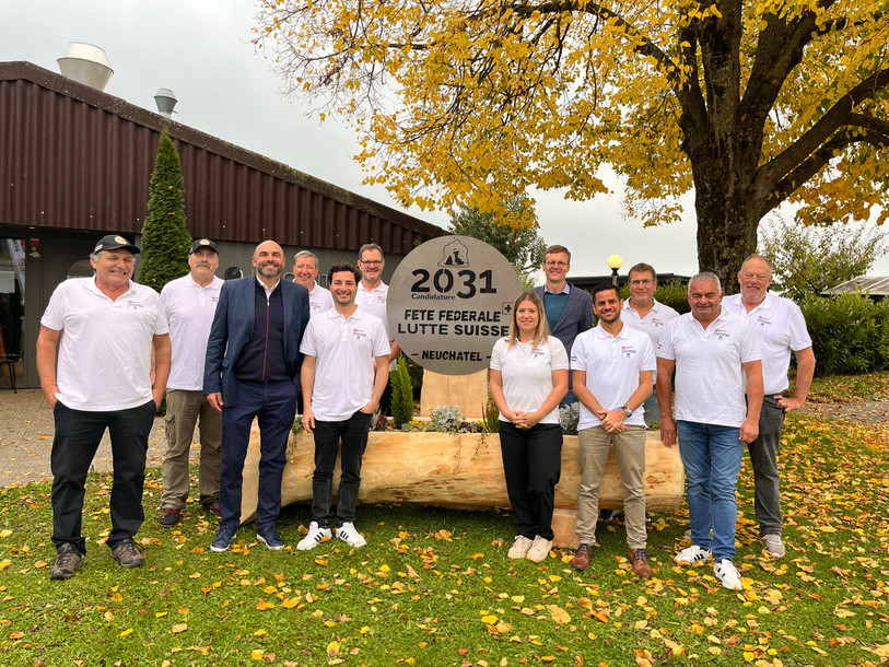 Le comité de candidature et les conseillers d’État Frédéric Mairy et Laurent Favre ont inauguré une fontaine en bois, symbole des fêtes de lutte suisse. (photo : comité de candidature neuchâtelois)