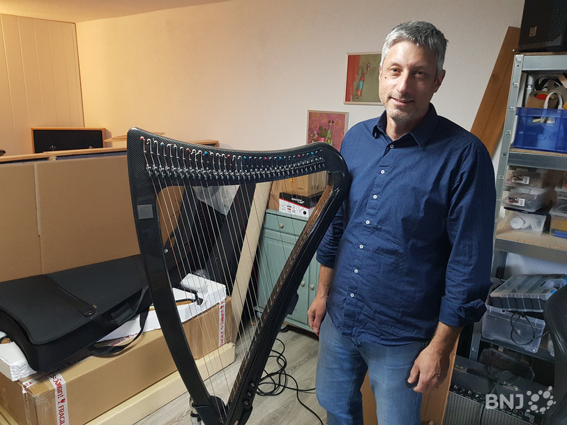 Frédéric Nicolet pose avec une des harpes qu'il a confectionnées à l'aide de ses deux associés.