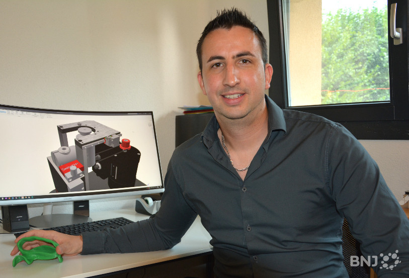 Bryan Gosparini tient dans sa main la première orthèse sortie de son imprimante 3D.