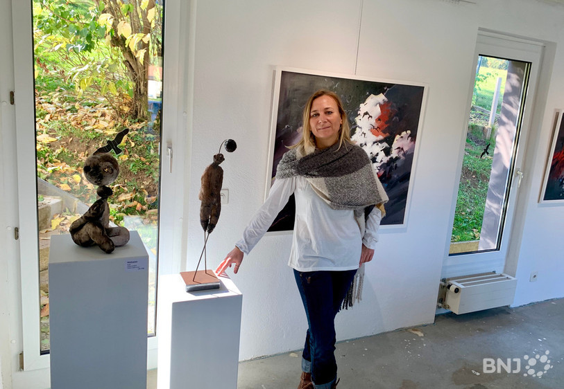 La sculptrice Lyne Héritier, devant l'une de ses statues et les tableaux de Sylvère Rebetez.
