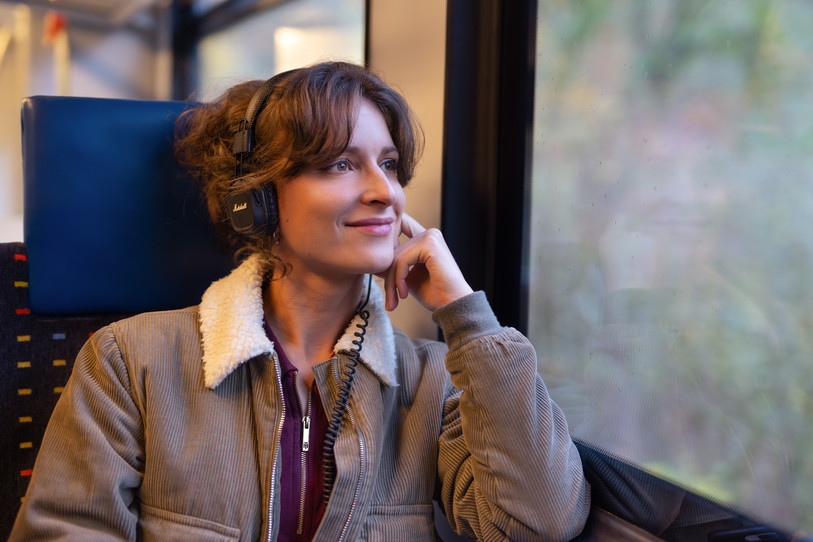 Jeune fille écoutant de la musique et regardant par la vitre du train.