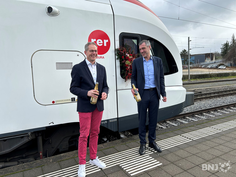 Le ministre jurassien des transports David Eray (à gauche) et le représentant des CFF David Fattebert ont symboliquement baptisé lundi la rame aux couleurs du nouveau RER Jura.