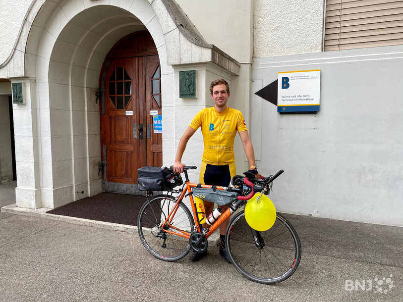 Joshua Drewlow pose devant la HES à Bienne au retour de son tour à vélo pour promouvoir l'informatique médicale.