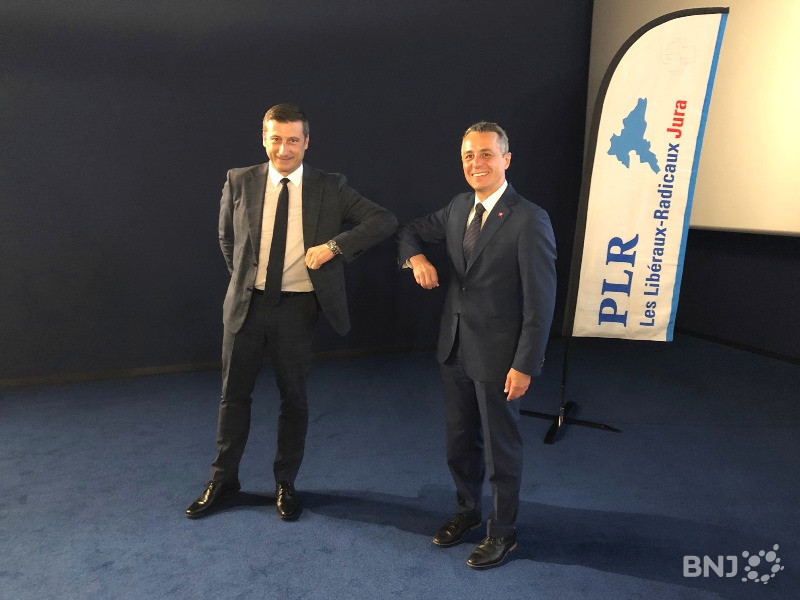 Le ministre PLR jurassien Jacques Gerber (à gauche) salue le Conseiller fédéral Ignazio Cassis - son collègue de parti - en mode « Covid ».