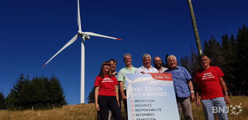 Le groupe de soutien au projet éolien des quatre bornes pose fièrement devant une éolienne du parc de Mont-Soleil. 