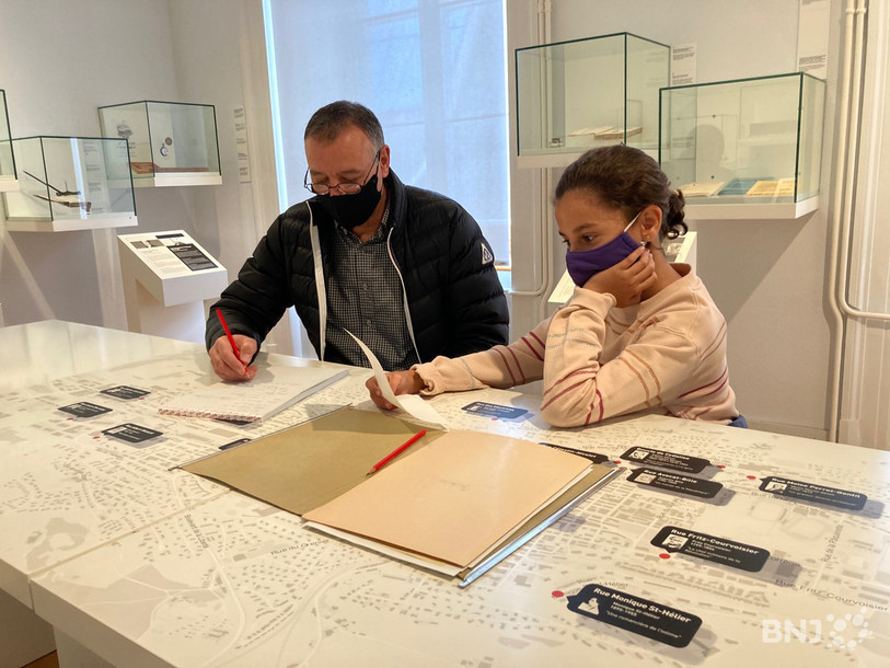 Les visiteurs du musée se penchent sur des dossiers d'enquête classés sans suite pour découvrir des indices. 