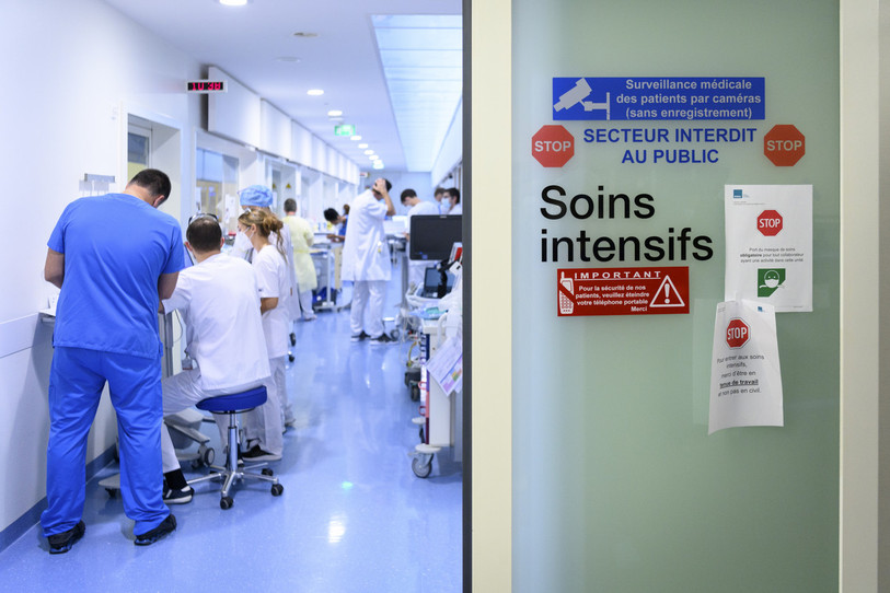 Du personnel médical se brief l'un l'autre alors qu'ils s'occupent de soigner des patients atteints du Covid-19 aux soins intensifs a l'hôpital Pourtalès. (Photo : archive KEYSTONE / Laurent Gillieron).
