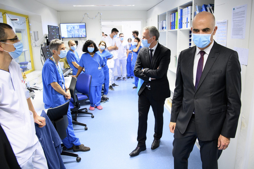 Le conseiller fédéral Alain Berset, à droite, et le conseiller d'Etat du canton de Neuchâtel Laurent Kurth, deuxième depuis la droite, parlent avec le personnel hospitalier lors de la visite des soins intensifs de l'hôpital Pourtalès du RHNe ce mercredi 16 decembre 2020 a Neuchatel. (KEYSTONE/Laurent Gillieron)