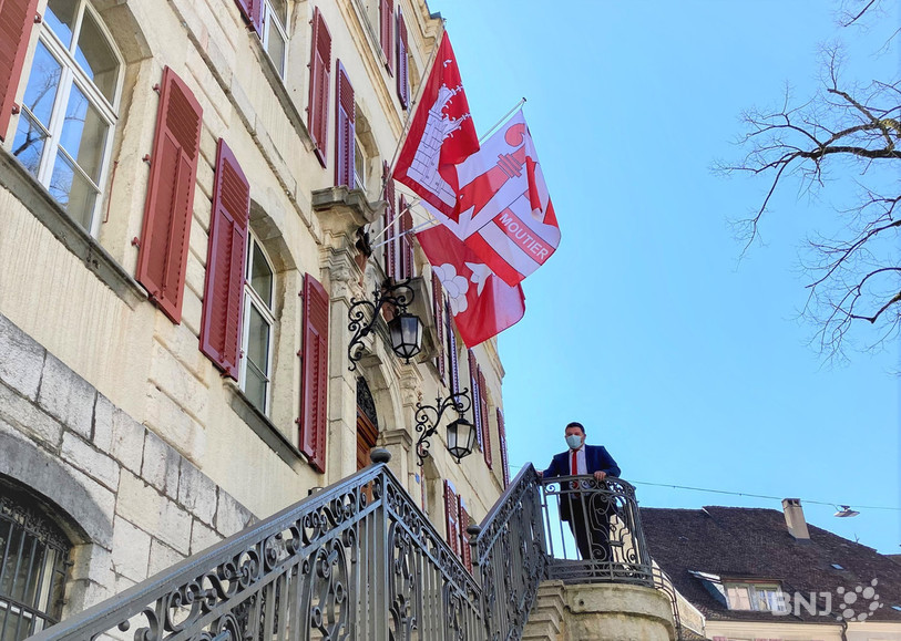 Le maire de Delémont Damien Chappuis pose sous le drapeau jurassien qui orne l'Hôtel de ville en soutien à Moutier.