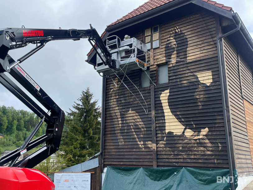 Antoine Guignard sur la nacelle, ici aux Calame, pour réaliser la 48e fresque de l'Exomusée du Locle.