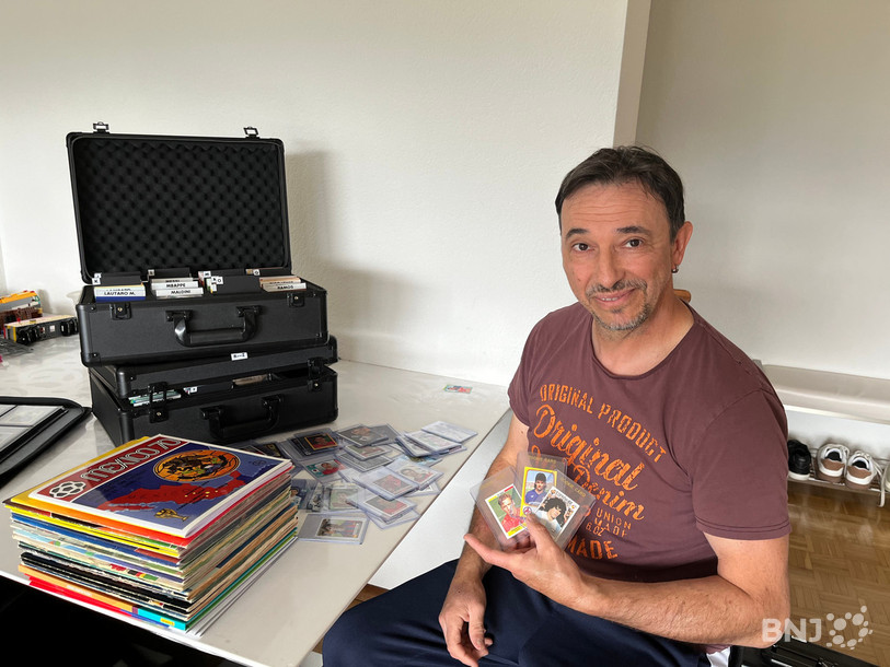 Rino Iassogna pose devant une partie de sa collection de vignettes.