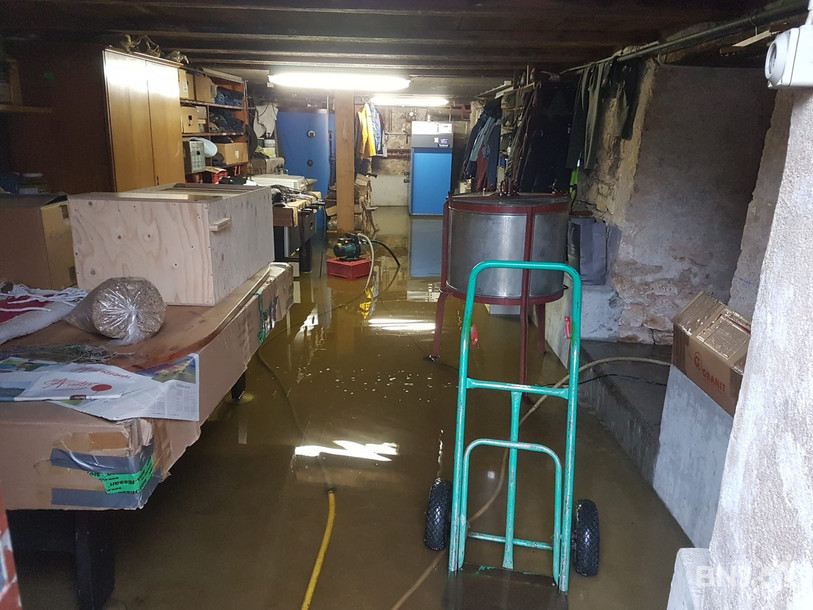 Dans sa cave, Anne-Marie tente de sauver sa chaudière en évacuant l'eau avec des pompes.