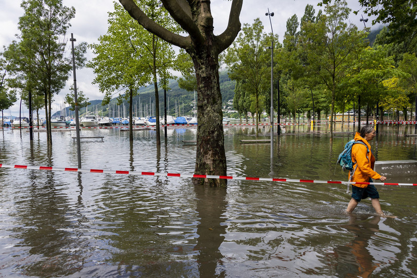 Une personne marche dans l'eau du lac dans le port lors de la montée de l'eau du lac de Bienne suite aux fortes précipitations des derniers jours. (Photo : KEYSTONE / Jean-Christophe Bott).