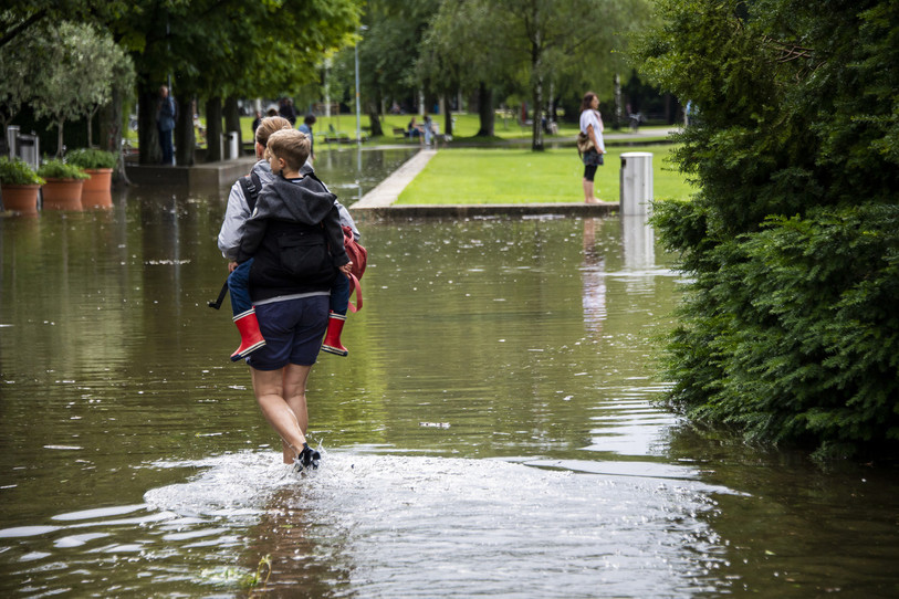 Des personnes marchent dans l'eau du lac dans le port lors de la montée de l'eau du lac de Bienne suite aux fortes précipitations des derniers jours le vendredi 16 juillet 2021 à Bienne. (Photo : KEYSTONE / Jean-Christophe Bott).