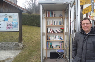 Christophe Calame devant la cabine téléphonique, qui fait office de centre culturel